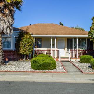 A suburban single-story house with a landscaped front yard and a small porch.