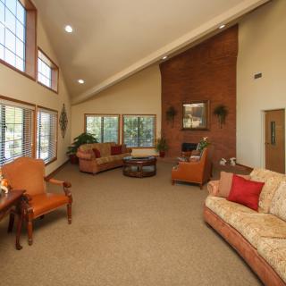 A spacious living room with high ceilings, featuring comfortable sofas and a fireplace.