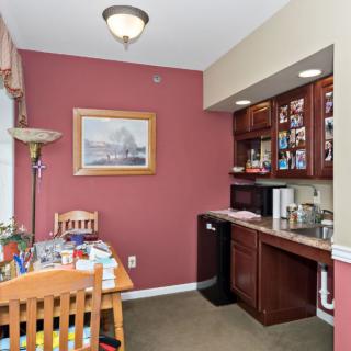 A cozy kitchenette with a dining area, featuring warm-colored walls, wooden cabinets, and a small dining table set.