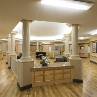 A modern lobby interior featuring a central reception desk with surrounding columns and wood flooring.