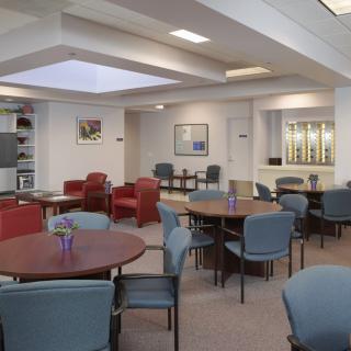 A spacious lounge area with tables and chairs arranged for communal seating.