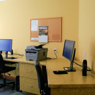 A modern office workstation featuring desks with computers, chairs, and a printer.