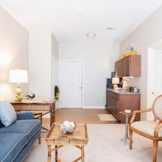 A cozy living room with a blue sofa, wooden coffee table, and adjacent kitchenette.