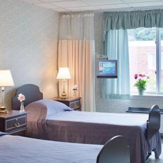 A hospital room with two beds, soft lighting, and a window view.