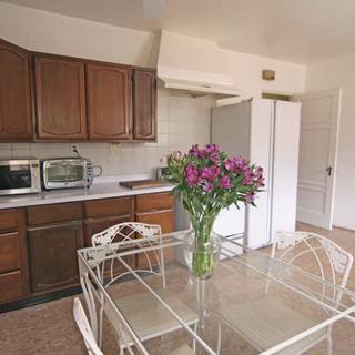 A cozy kitchen with wooden cabinets, a dining table adorned with fresh flowers, and various appliances.