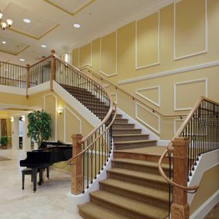 A luxurious foyer featuring a grand staircase and a black piano.