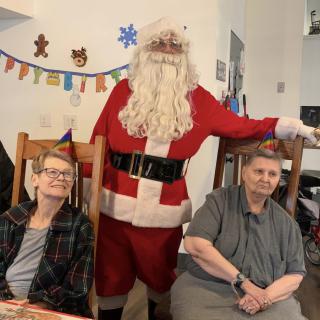 Santa Claus posing with two people during a holiday celebration.