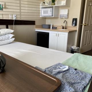 A well-equipped hospital room featuring a patient bed, microwave, and sink.