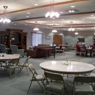 A spacious community center meeting room with round tables and folding chairs.