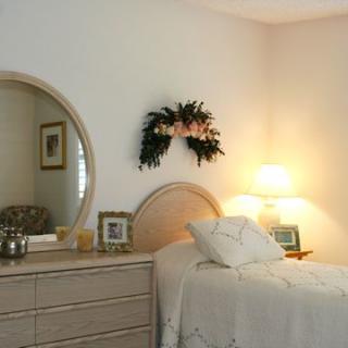 A cozy bedroom with a mirror, lamp, and floral decor.