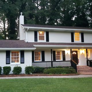 A cozy two-story suburban house surrounded by trees.