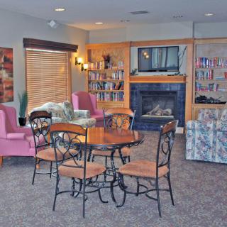 A cozy living room with a seating area, table, and fireplace surrounded by bookshelves.