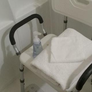 A shower chair equipped with towels and a bottle of liquid soap for personal care.