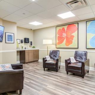 A modern waiting room featuring comfortable chairs and vibrant artwork on the walls.