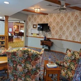 A cozy living room with floral-patterned couches and classic wallpaper.