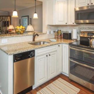 A modern kitchen with white cabinets and stainless steel appliances.