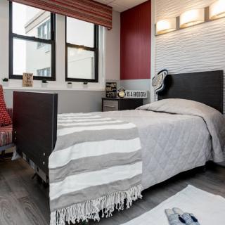 A modern bedroom with stylish decor, featuring a bed with a striped blanket and contemporary lighting.