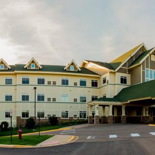 A picturesque view of a large hotel building with green roofs under a partly cloudy sky.
