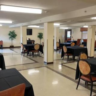 A spacious dining area with tables and chairs, decorated with potted plants.