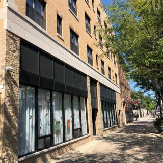 A modern urban building with a tree-lined sidewalk on a sunny day.