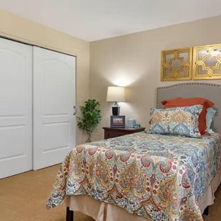 A cozy bedroom with a single bed, patterned bedding, and warm lighting.