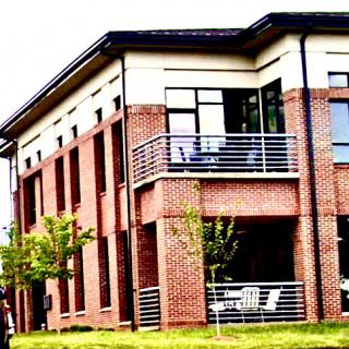 A modern brick building featuring balconies and green landscaping.
