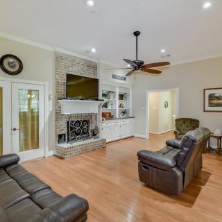 A cozy living room featuring leather sofas, a stone fireplace with a mounted TV, and hardwood flooring.