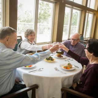 A group of seniors enjoying a meal together and toasting at a restaurant.