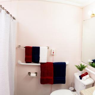 A neatly organized bathroom with red, white, and blue towels hanging on a rack, a sink with a mirror above it, and a white shower curtain.