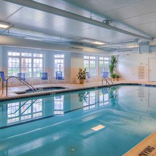 Indoor swimming pool with natural lighting and seating area.
