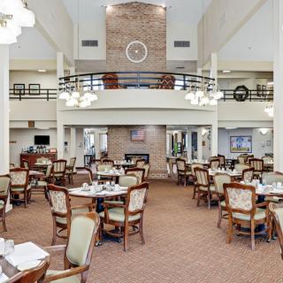 Spacious dining area with elegantly set tables and chairs, featuring a high ceiling and chandeliers.