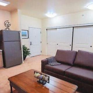 A cozy living room with a brown sofa, coffee table, and a fridge in the corner.