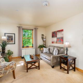 A cozy living room with a sofa, armchair, and various decorations.