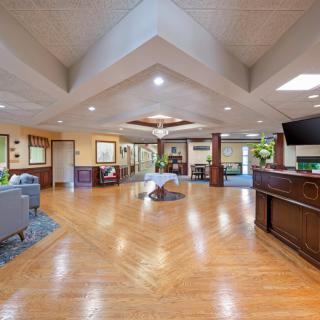 A spacious and modern lobby with wooden flooring, comfortable seating, and decorative plants.