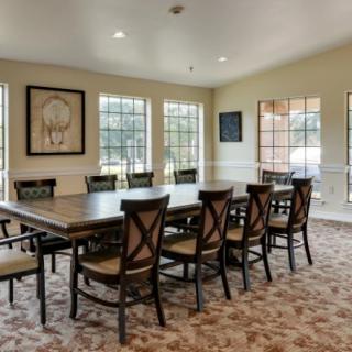 A spacious conference room with a long meeting table and several chairs, surrounded by large windows providing natural light.