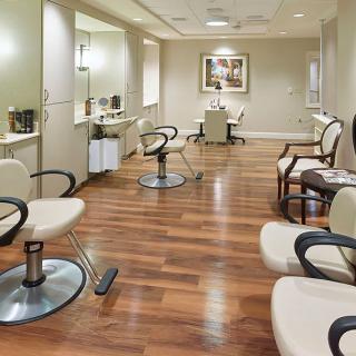 A modern hair salon interior with styling chairs, mirrors, and a wooden floor.