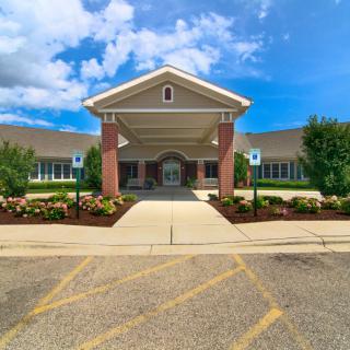A well-maintained building entrance with attractive landscaping under a bright blue sky.
