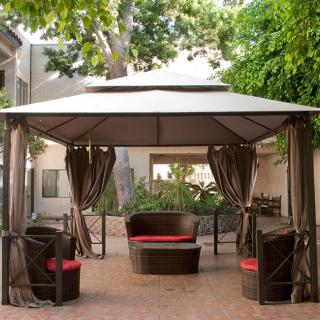 A cozy outdoor gazebo with seating set amidst a lush garden.