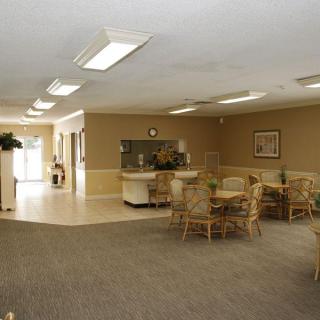 A spacious lobby area with tables, chairs, and a reception desk.