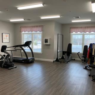 A well-lit gym with various fitness equipment including a treadmill and exercise bike.