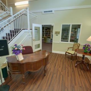 A welcoming lobby area with a wooden reception desk, chairs, and a staircase.