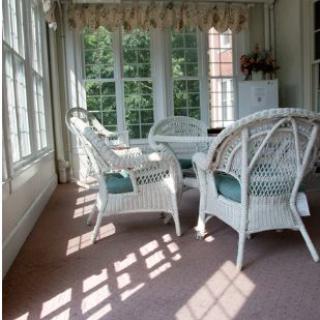 A sunlit room with wicker furniture and large windows.