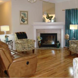 A cozy living room featuring comfortable armchairs, a fireplace, and wooden flooring.