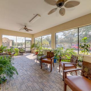 A bright sunroom with large windows, indoor plants, and comfortable seating.