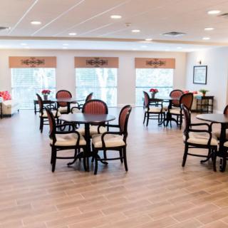 A bright and spacious dining area with multiple tables and chairs, featuring large windows.