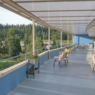 A spacious outdoor balcony with seating arrangements overlooking a scenic forest view.