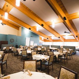 A spacious dining area set up for an event, featuring round tables and elegant decor.