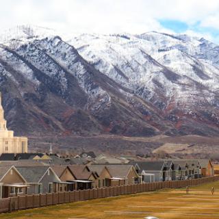 A picturesque view of a neighborhood with homes in the foreground and snow-capped mountains in the background.