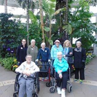A group of people in a conservatory surrounded by lush greenery.