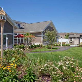 A picturesque building surrounded by a well-maintained garden and lawn on a sunny day.